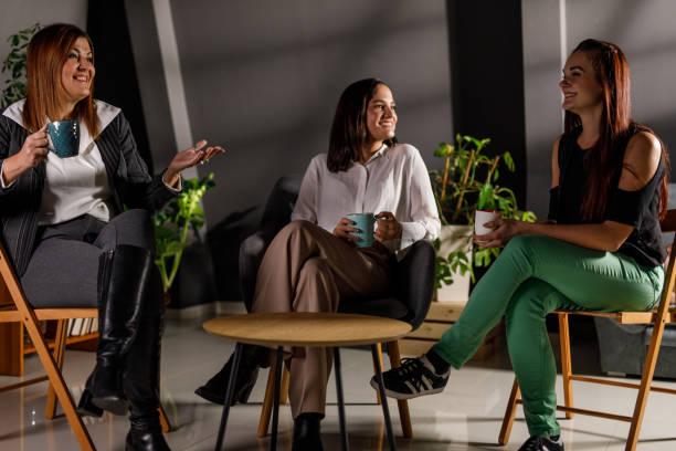 Three women chatting over coffee in a supportive community moment